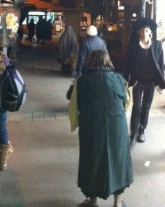 Jewish woman in Jerusalem shuk wearing cloak.