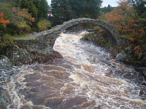 river rapids flowing under bridge